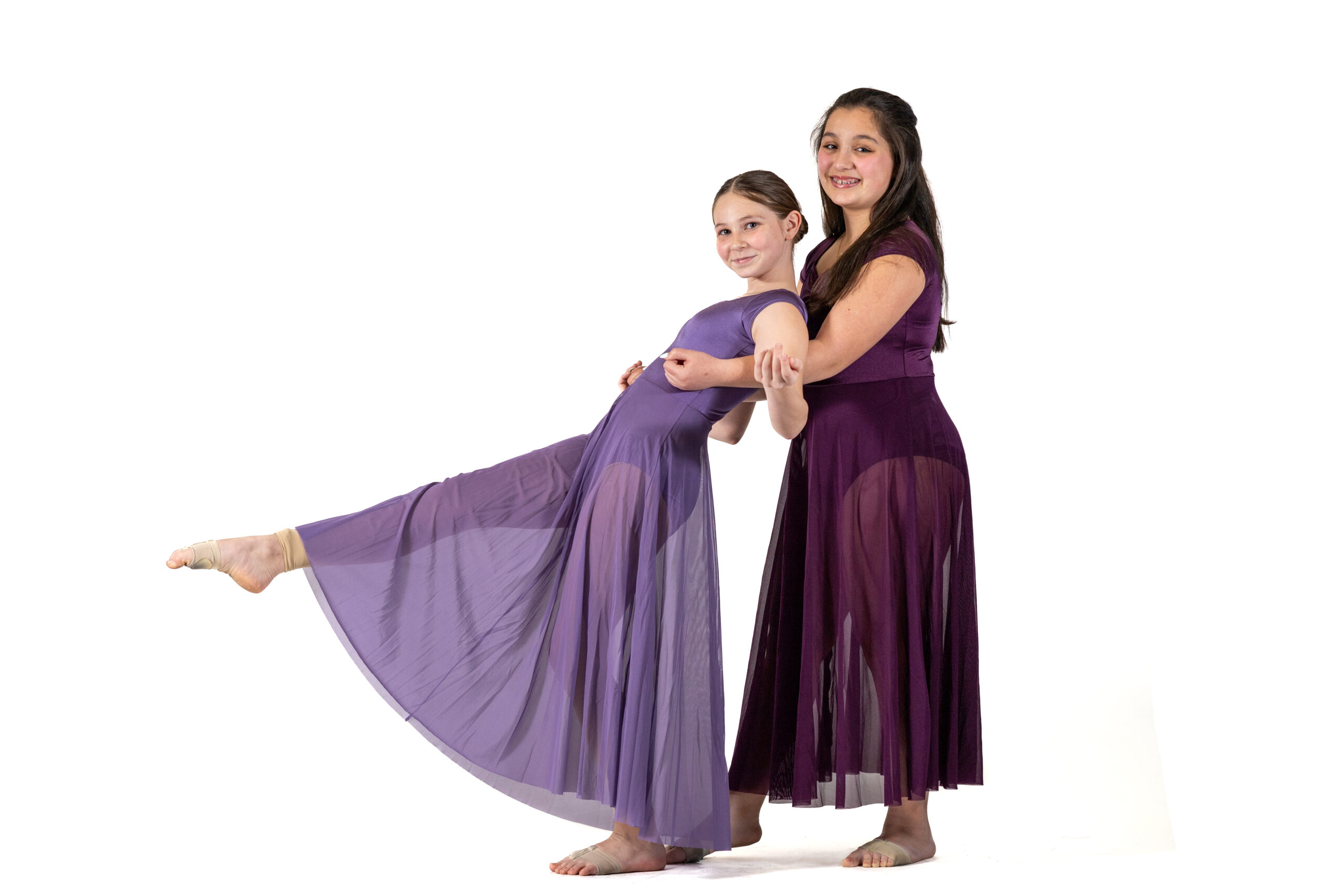 Two Symmetry Dance Company dancers pose in purple costumes for Senior Company